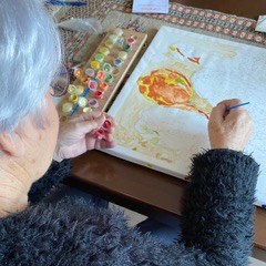 Iemand die aan tafel een schilderij maakt